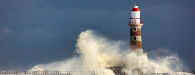 waves crashing against a lighthouse in a storm
