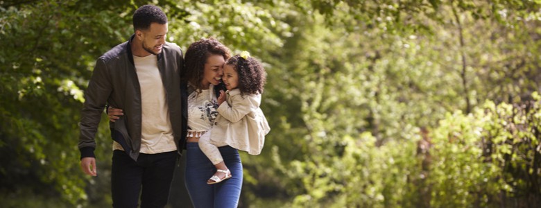 A family of three walking through some woods