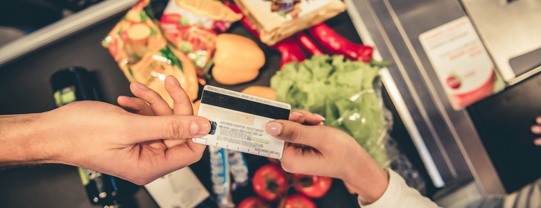 A customer handing over a bank card to pay for goods in a supermarket.