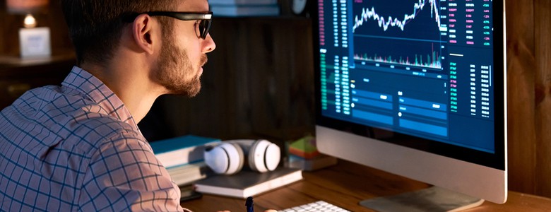 A man looking at graphs and data on a computer screen.