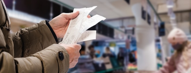 A person holding up a receipt in a supermarket.