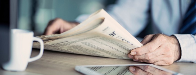 A man reading a newspaper at a table.