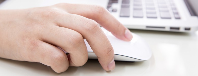 A person typing on a laptop keyboard and using a mouse.