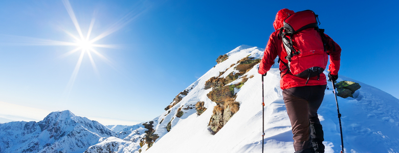 A climber at the top of a snowy peak.