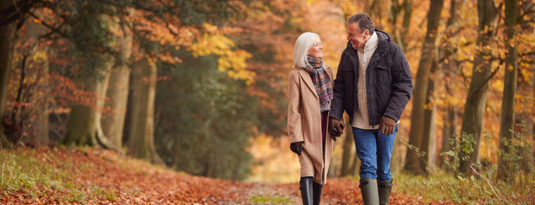 An older couple walking through woodland.