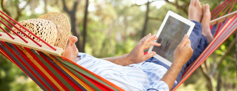 A man in a hammock using a tablet.