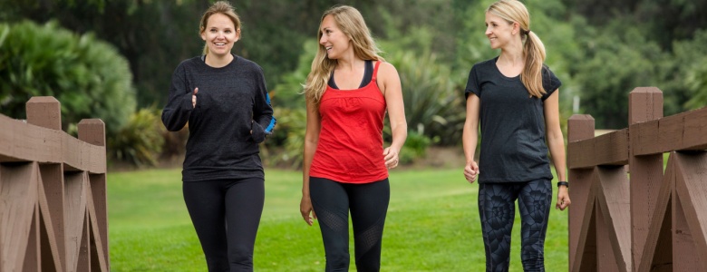 Three women in gym clothes walking over a bridge