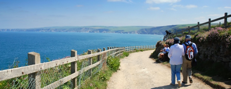 Two people walking along the coast in Port Isaac, Cornwall