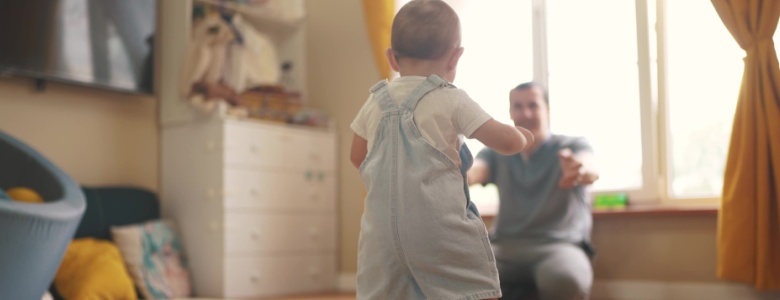 A toddler walking towards a parent.