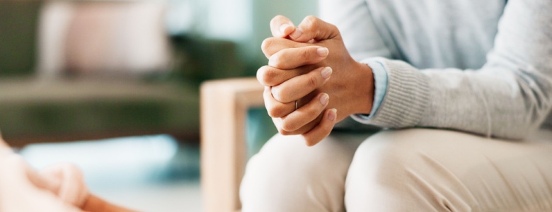 A woman sitting with her hands clasped.