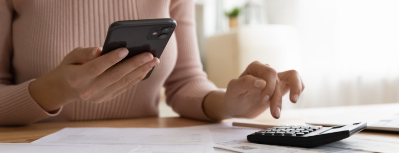 A woman using a phone and calculator.