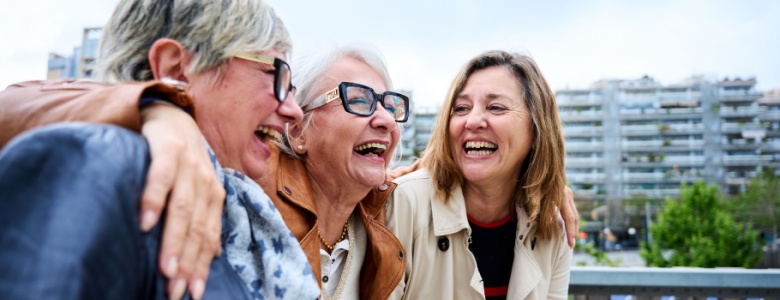 Three women with the around each other laughing.