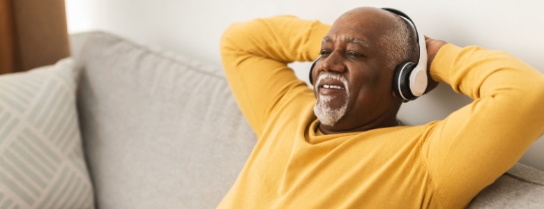A man relaxing on a sofa with his hands behind his head.