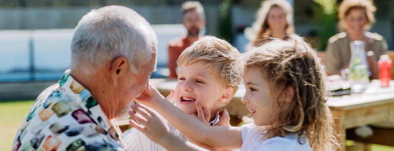 A grandfather playing with his grandchildren outdoors.