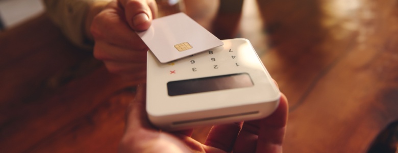 A person using their debit card to pay in a café.
