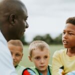 A man coaching a junior football team.