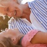 A grandmother playing with her granddaughter outside.