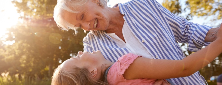 A grandmother playing with her granddaughter outside.