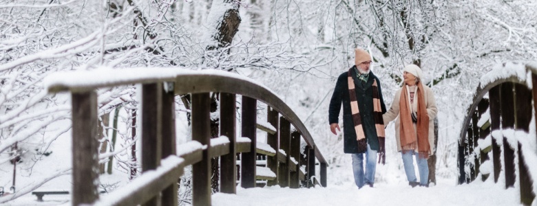 A couple walking across a bridge in the snow.
