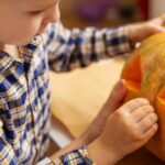 A child carving a pumpkin.