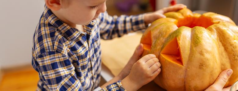 A child carving a pumpkin.
