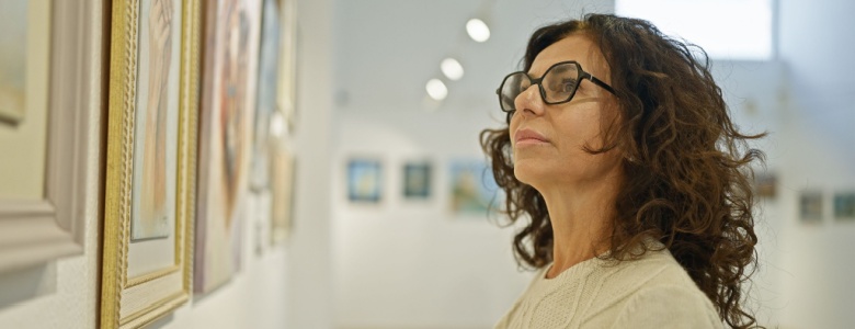 A woman looking at a painting in an art gallery.