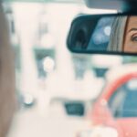 A driver adjusting the rear view mirror in a car.