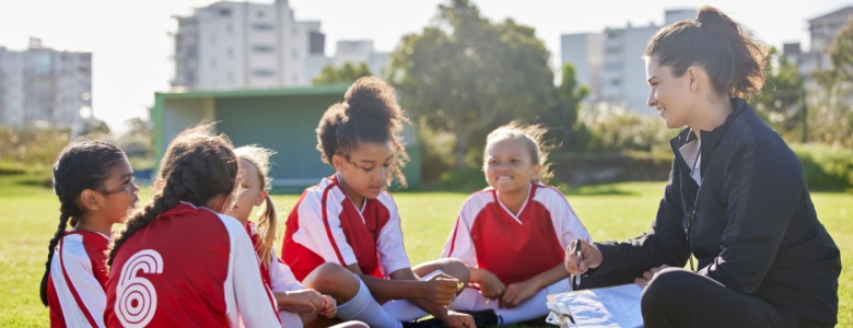 A woman coaching a girl’s football team.