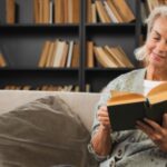 Smiling lady sitting on a sofa reading a book
