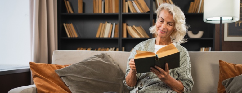 Smiling lady sitting on a sofa reading a book