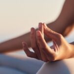 A woman sitting in the lotus position mediating.
