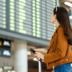A woman looking at a departure board in an airport.