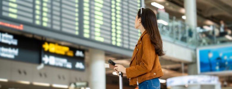 A woman looking at a departure board in an airport.