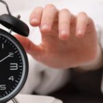 A person reaching to turn off an alarm clock.