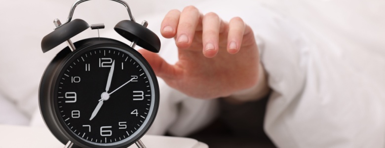 A person reaching to turn off an alarm clock.