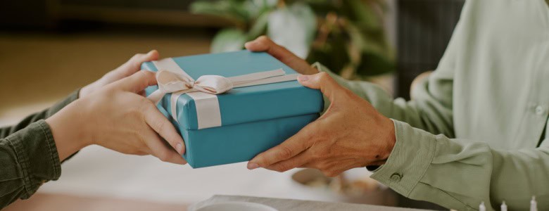A person gifting a wrapped birthday present.
