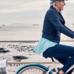 A woman cycling along a beachfront.