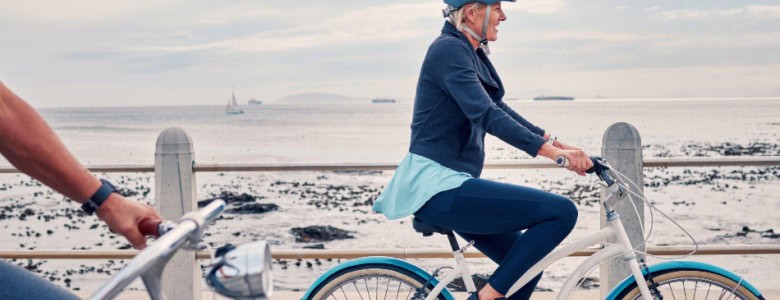 A woman cycling along a beachfront.