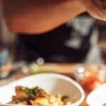 A man adding garnishes to a meal.