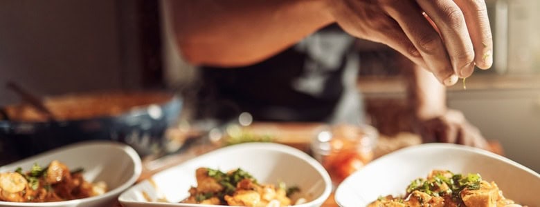 A man adding garnishes to a meal.