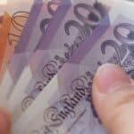 A person holding UK bank notes.