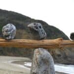 Rocks balancing on log on top of another rock