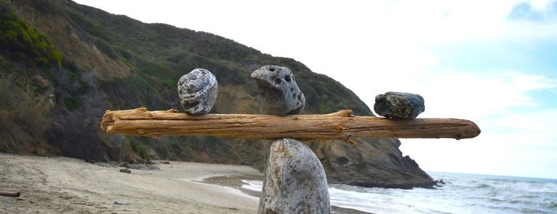 Rocks balancing on log on top of another rock